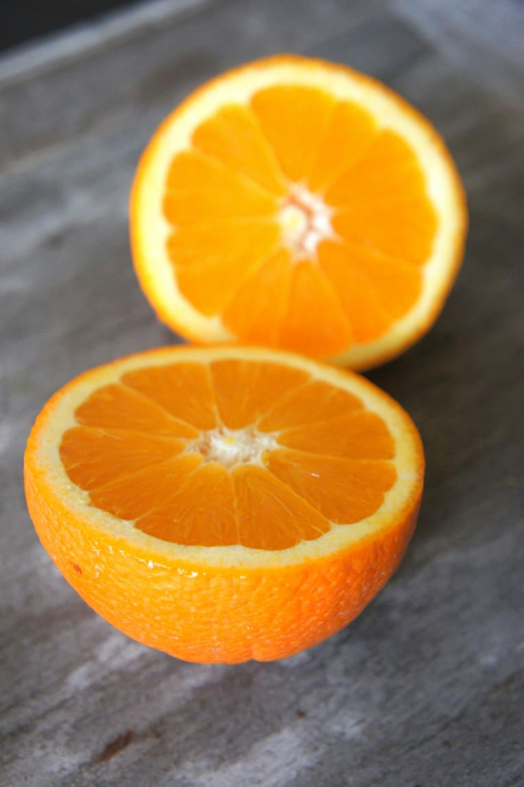 An orange cut in half on a granite countertop.