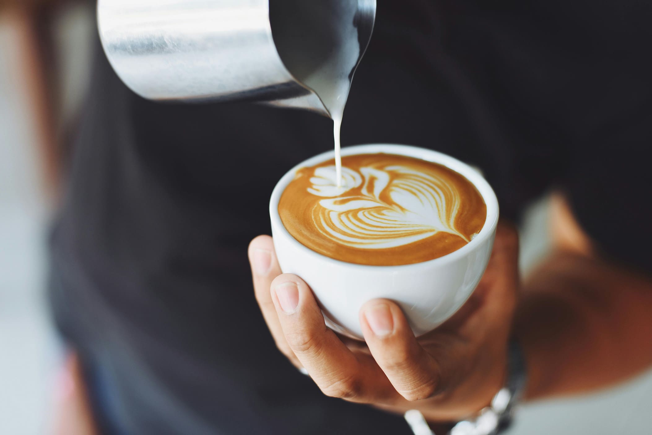 A person holding coffee mug with healthy coffee creamers and sweeteners